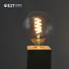 A close-up shot of a vintage-style LED light bulb with a spiral filament, mounted on a dark base. Produktbild-Vorschau