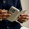A person is holding a phone with a wallet case attached. Náhled obrázku produktu