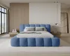 A bedroom with a blue upholstered bed as the main focus. Voir les images du produit