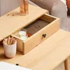 A close-up view of a wooden desk with an open drawer, showing pencils in a cup, two candles in glasses, and a book inside the drawer. Produktbild-Vorschau