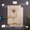 A piece of birch plywood with a flower design burned onto it, next to a wood-burning tool and other sheets of plywood. Produktbild-Vorschau