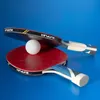 Two table tennis paddles and a ball are arranged on a blue surface. Produktbild-Vorschau
