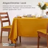 A dining table set with a mustard yellow tablecloth, placemats, and chairs. Anteprima dell’immagine prodotto