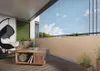 A balcony furnished with a hanging chair, coffee table, and plants, featuring a beige privacy screen along the railing. Produktbild-Vorschau