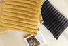 Two corduroy pillows, one mustard yellow and one dark gray, are placed on a textured white surface. A magazine is partially visible beneath the mustard pillow. Produktbild-Vorschau