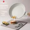 A frying pan is shown tilted, with an egg sliding out of it towards a sandwich and avocado slices on a gray surface. The background is light gray. Náhled obrázku produktu