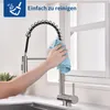 A hand is cleaning a kitchen faucet with a blue cloth. Podgląd zdjęcia produktu