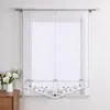 A white sheer curtain with gray embroidery hangs on a window. Produktbild-Vorschau