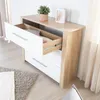 A dresser with one drawer open, showing clothes inside, in a room with a rug and curtains. Anteprima dell’immagine prodotto