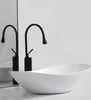 A white oval washbasin with two black faucets in front of a mirrored background. Náhľad obrázku produktu