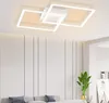 A modern white ceiling lamp with square frames is shown in a well-lit room with a white paneled wall and a sofa in the foreground. Podgląd zdjęcia produktu