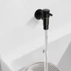 A black wall-mounted faucet with water flowing into a white sink with a metal drain. Podgląd zdjęcia produktu