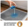 A hand pouring blue liquid onto a grey training pad. Produktbild-Vorschau