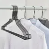 A close-up shot of black metal hangers holding shirts on a white rod. Produktbild-Vorschau