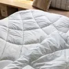 A close-up view of a white quilted comforter. Produktbild-Vorschau