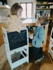 Two children are drawing on a chalkboard easel in a kitchen. Anteprima dell’immagine prodotto