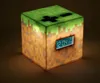 A Minecraft-themed alarm clock cube is shown on a brown surface, illuminated from within. Náhľad obrázku produktu