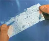 Hands holding a strip of repair tape with water droplets on it, against a blue background. Produktbild-Vorschau