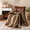 A cozy living room scene with a brown leather armchair draped with a furry blanket, next to a fireplace and a plant. Náhled obrázku produktu