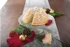 A festive Christmas-themed table setting with a bundt cake shaped like a pine forest, decorated with powdered sugar and red berries, alongside pinecones and ornaments. Anteprima dell’immagine prodotto