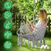 A woman is reading a book while sitting in a hanging chair in a garden. Náhled obrázku produktu