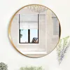 A round gold-framed mirror hangs on a white wall, reflecting a room with a window, blinds, and a chandelier. Produktbild-Vorschau