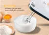 A white electric hand mixer is shown in use, whipping cream in a clear bowl. Ingredients like eggs and flour are visible nearby, suggesting a baking context. Produktbild-Vorschau