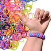A hand wearing a bracelet made of colorful rubber bands, surrounded by a large pile of loose rubber bands. Podgląd zdjęcia produktu