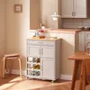 A kitchen cart with wine storage and drawers, placed in a kitchen or dining area. Voir les images du produit