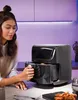 A woman is using an air fryer in a kitchen setting. Produktbild-Vorschau