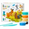 A box of HeyClay Dog Story air-dry clay kit with various dog figures made from the clay, and several tubs of clay and tools in the foreground. Podgląd zdjęcia produktu