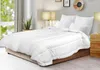 A white comforter is laid out on a bed in a bedroom setting. Voir les images du produit