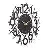 A black, modern wall clock with abstract numbers and gold hands, set against a white background. Produktbild-Vorschau