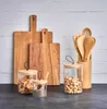 A collection of kitchen utensils and storage jars arranged on a dark countertop against a white brick wall. Podgląd zdjęcia produktu