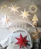 A collection of festive Christmas decorations, including paper stars, wreaths, and candle arches, arranged on a mantelpiece. Podgląd zdjęcia produktu