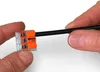 Hands holding a WAGO 221 series wire connector with a black wire inserted. Podgląd zdjęcia produktu