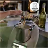 A person is holding a kitchen utensil with food residue over a kitchen appliance. A bottle of wine and eggs are in the background. Produktbild-Vorschau