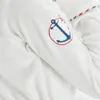 A close-up of a white bathrobe sleeve with a blue and red anchor embroidery. Produktbild-Vorschau