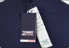 A close-up of a navy blue t-shirt with two tags attached. Voir les images du produit