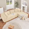 A beige sectional sofa in a living room setting with a fireplace and doors in the background. Produktbild-Vorschau