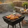 A barbecue grill with food cooking on it, set on an outdoor patio. Produktbild-Vorschau