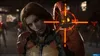 A close-up of a character with dramatic makeup and armor, with a targeting reticle overlayed on the image. Other characters are visible in the background. Produktbild-Vorschau