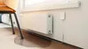 A water leak sensor is shown next to a radiator, with water pooled on the floor. Podgląd zdjęcia produktu