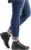 A person's legs wearing blue jeans and black ankle boots. Produktbild-Vorschau