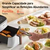An air fryer with cooked food, including chicken and vegetables, being served onto plates. Náhľad obrázku produktu