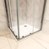 Close-up view of the corner of a shower cabin with a white base and glass doors, set against tiled walls and floor. Produktbild-Vorschau