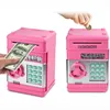 A pink electronic piggy bank with a keypad and coin slot, shown from two angles. One angle shows a hand inserting a dollar bill, and the other shows a hand inserting a coin. Náhľad obrázku produktu