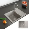 A beige kitchen sink with a chrome faucet is shown on a dark gray countertop, with some vegetables and chives in the foreground. Anteprima dell’immagine prodotto