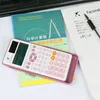 A pink scientific calculator is placed on top of books, with a notebook and pen to the right. Podgląd zdjęcia produktu