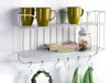 A white metal kitchen shelf with mugs, a jar of cookies, and folded towels. Náhľad obrázku produktu